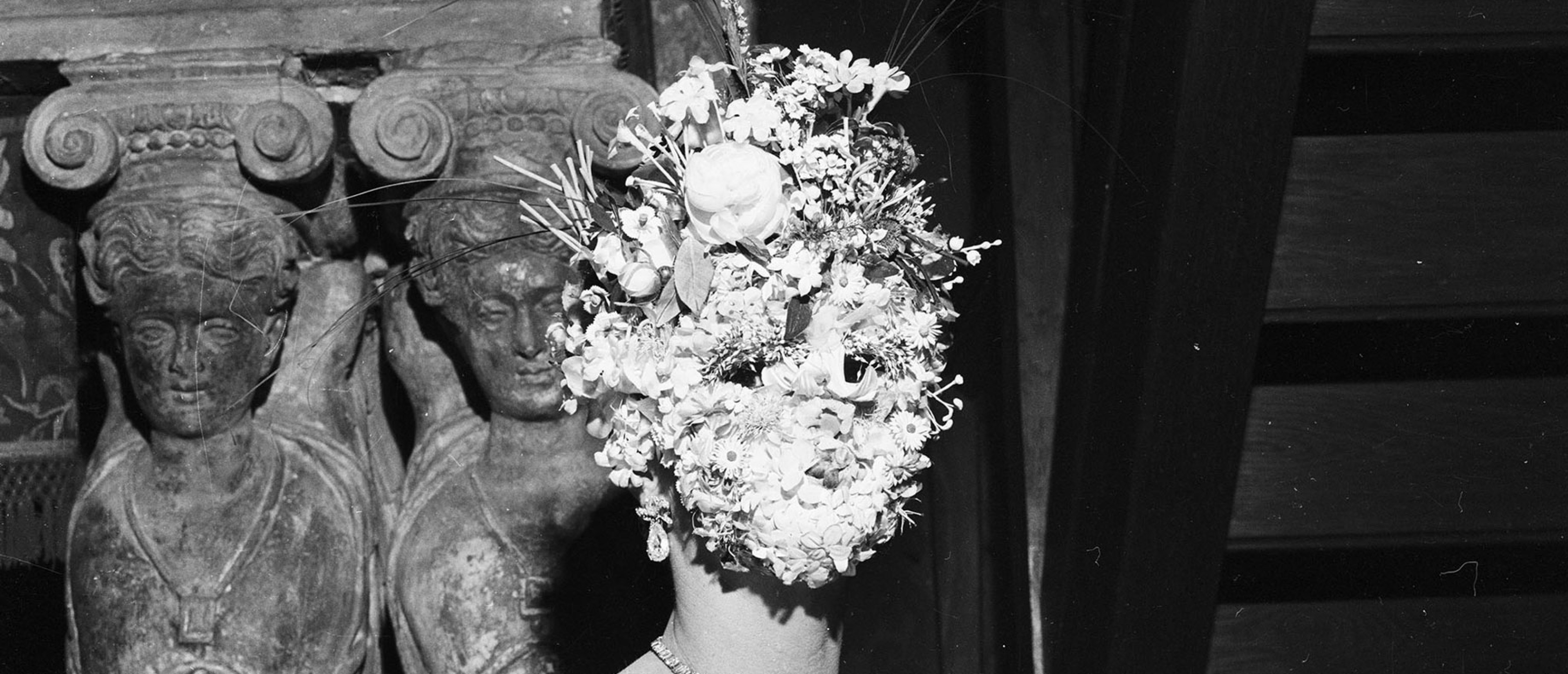 Person mit einer Maske aus Blumen vor dem Gesicht