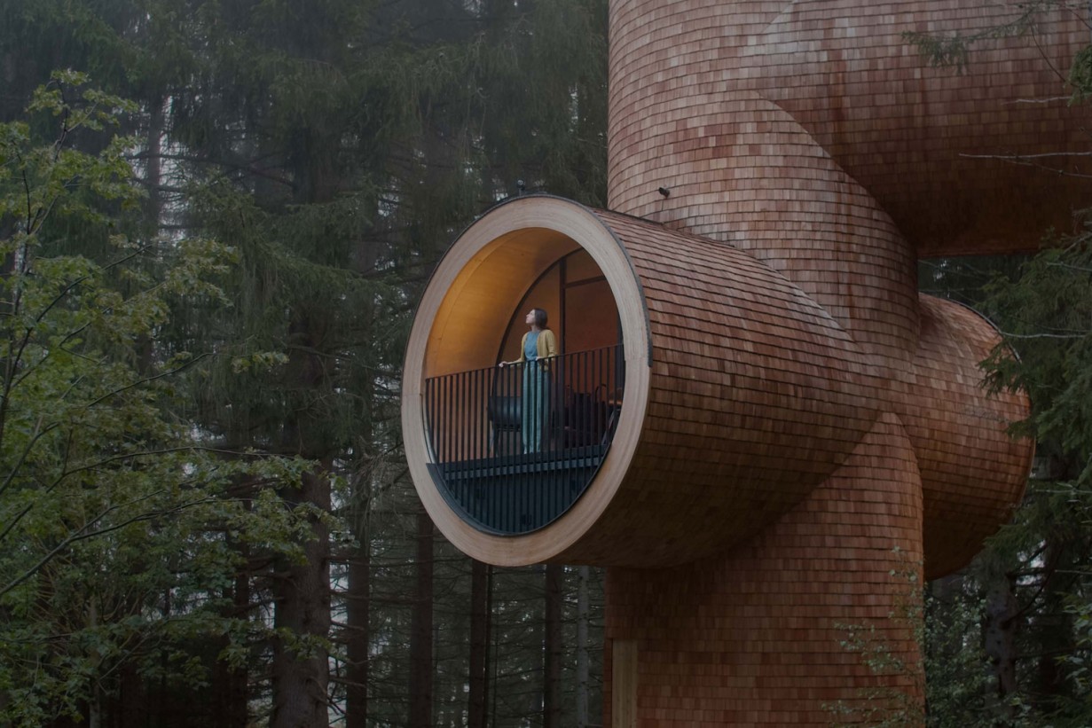Ein überdimensionales Baumhaus in Rohrform in Mitten eines Waldes.